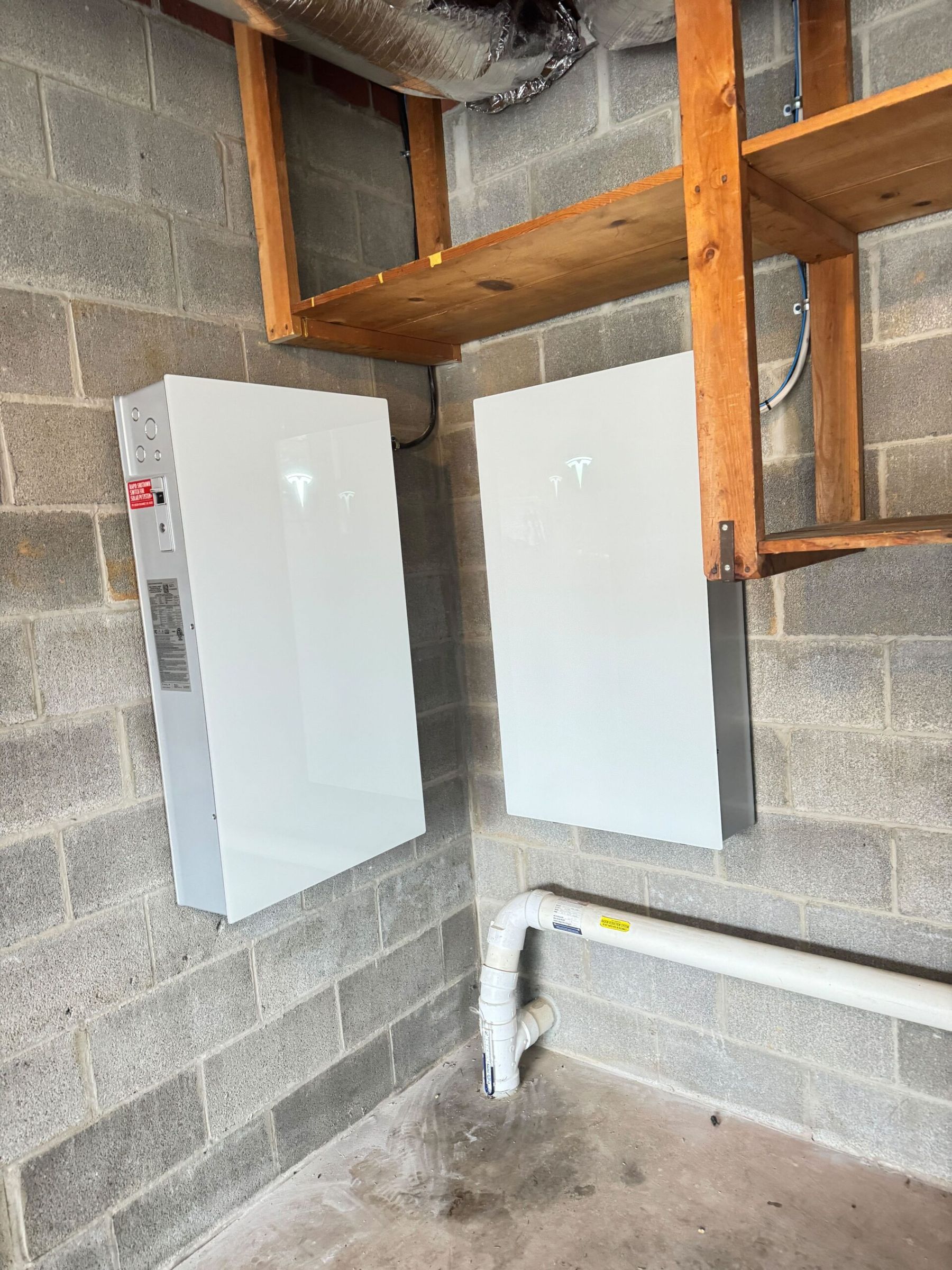 Tesla Powerwall 3 and backup gateway mounted on a basement cinder-block wall.